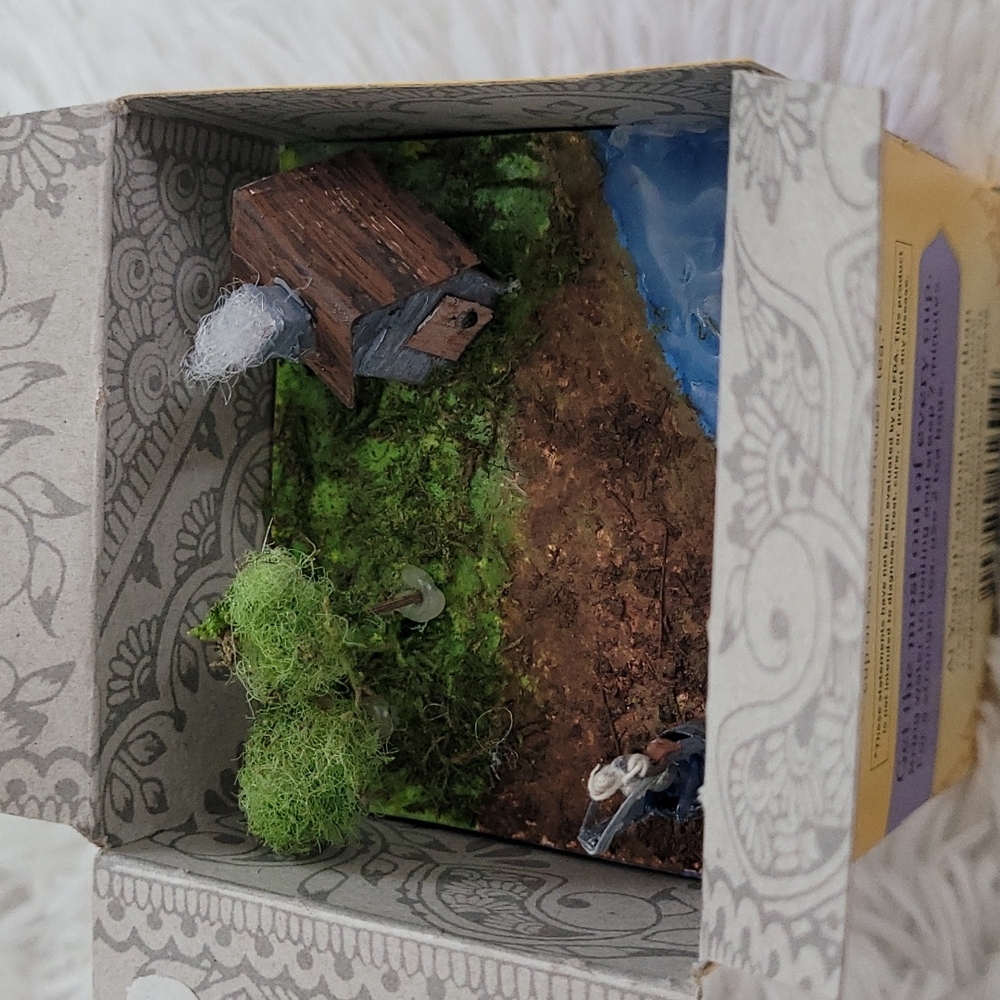 Miniature gift, hand made cabin, pond, wishing well, and trees inside of tea box